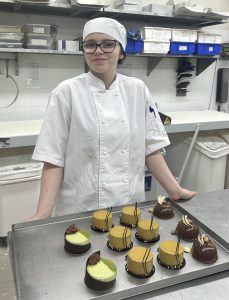 A girl is standing in front of cakes