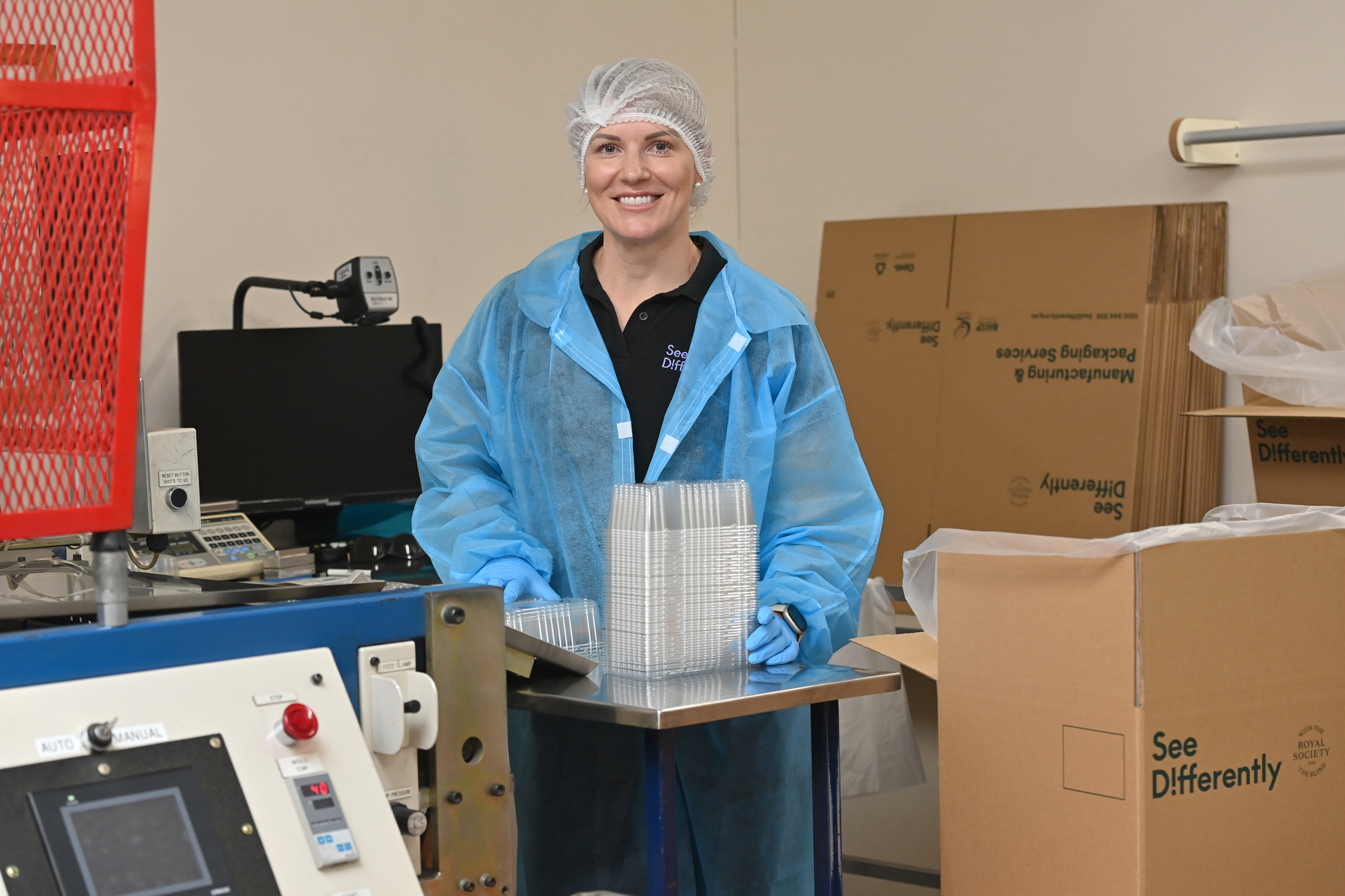 Innovation Thermoforming - Man wearing hi-vis see differently shirt, smiling and waving in front of a thermoforming machine